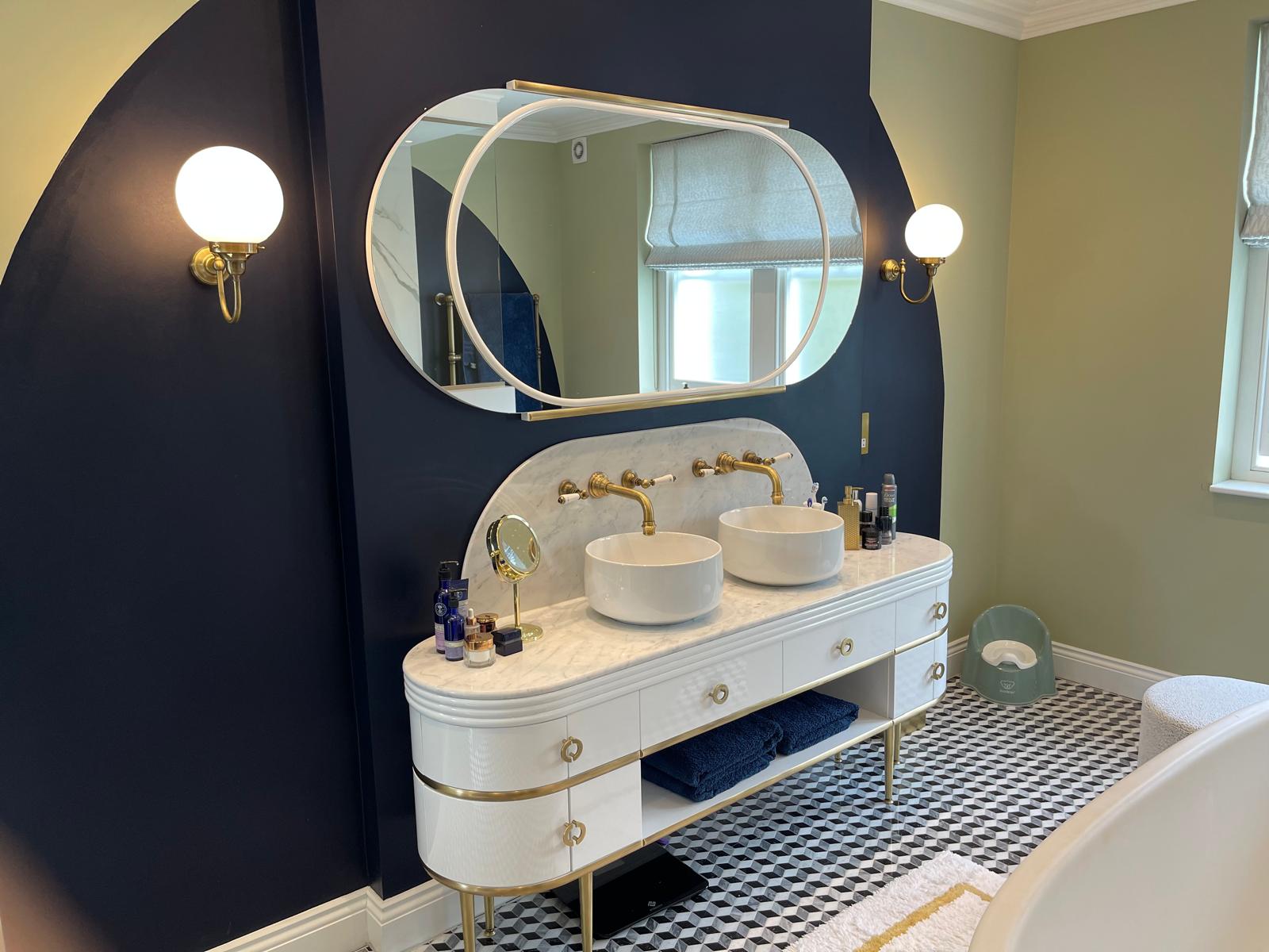 Completed New Level bathroom with curved vanity, brass details and dark blue wall
